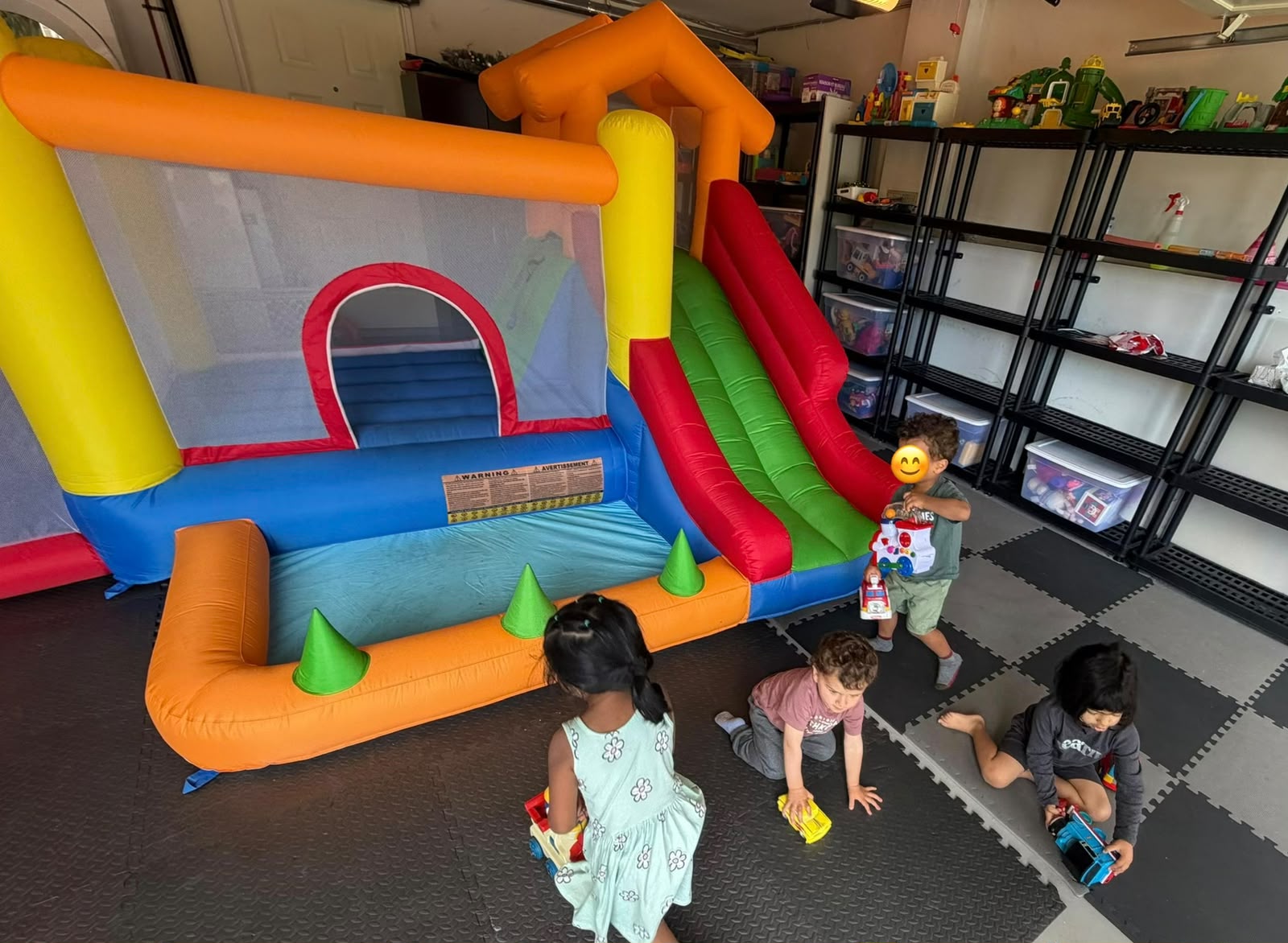 Children playing near a colorful indoor bouncy play area