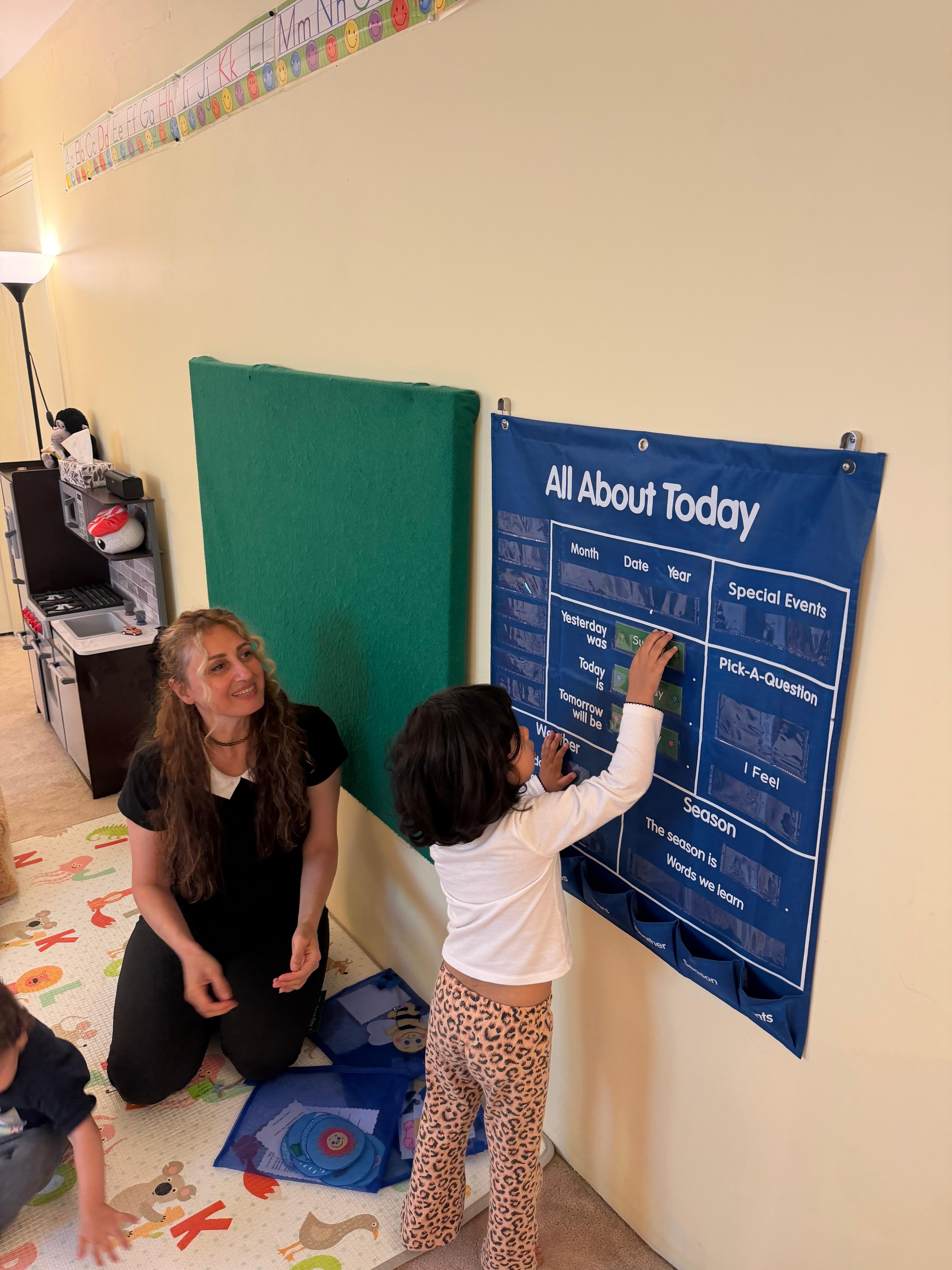 Child helping with the classroom calendar beside the educator