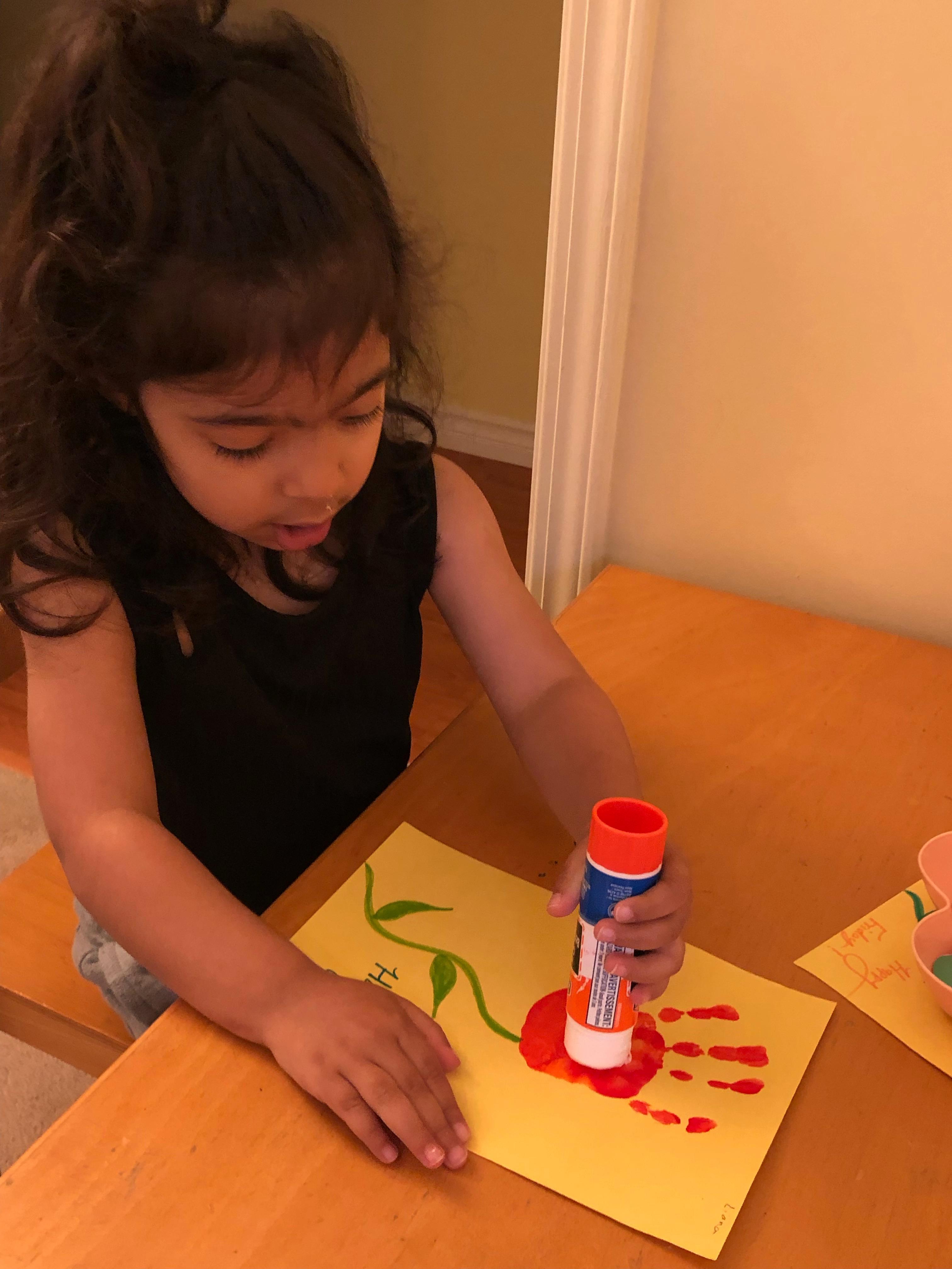 Child creating flower art with paper and glue