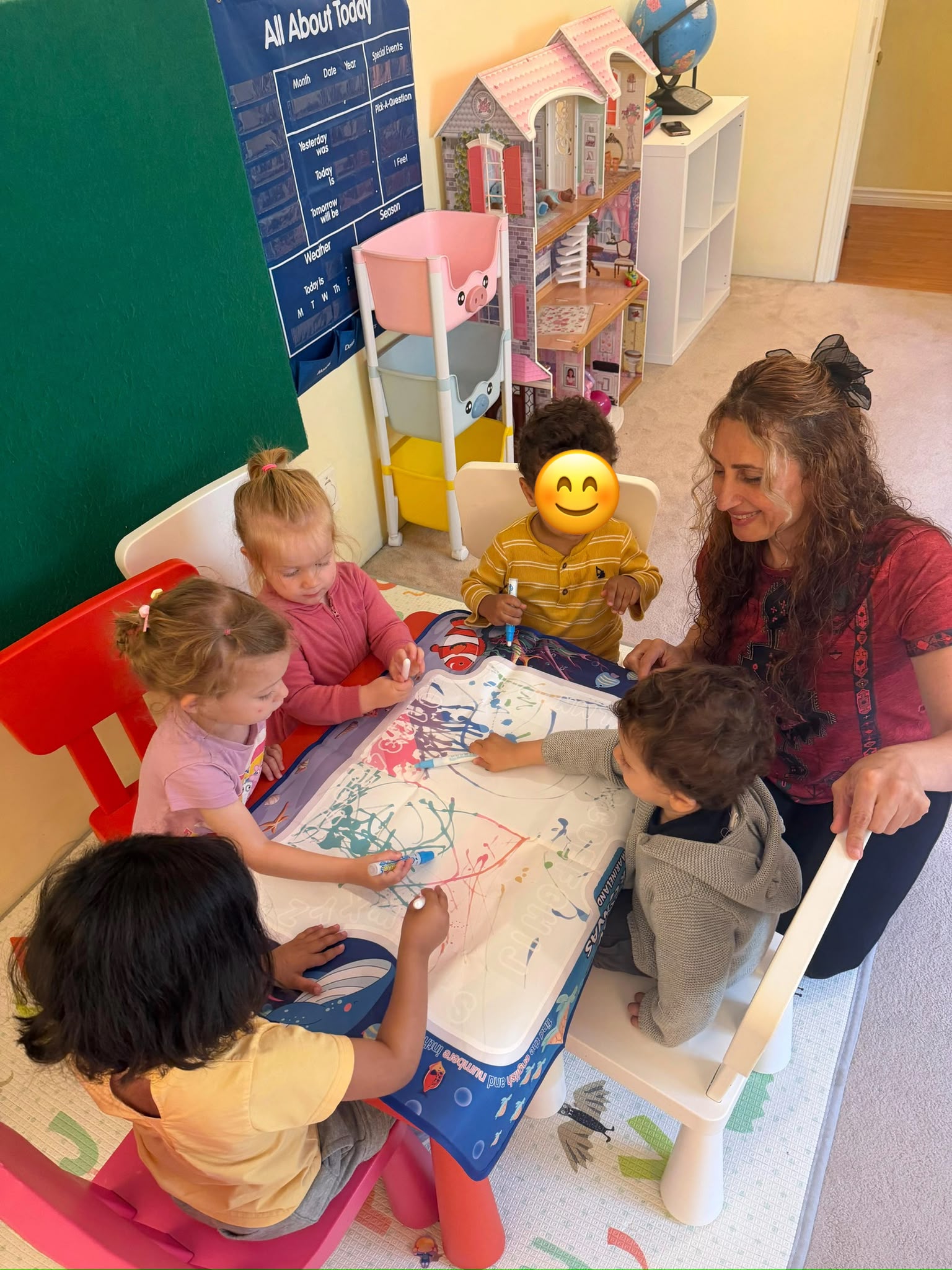 Children and educator drawing together at a classroom table