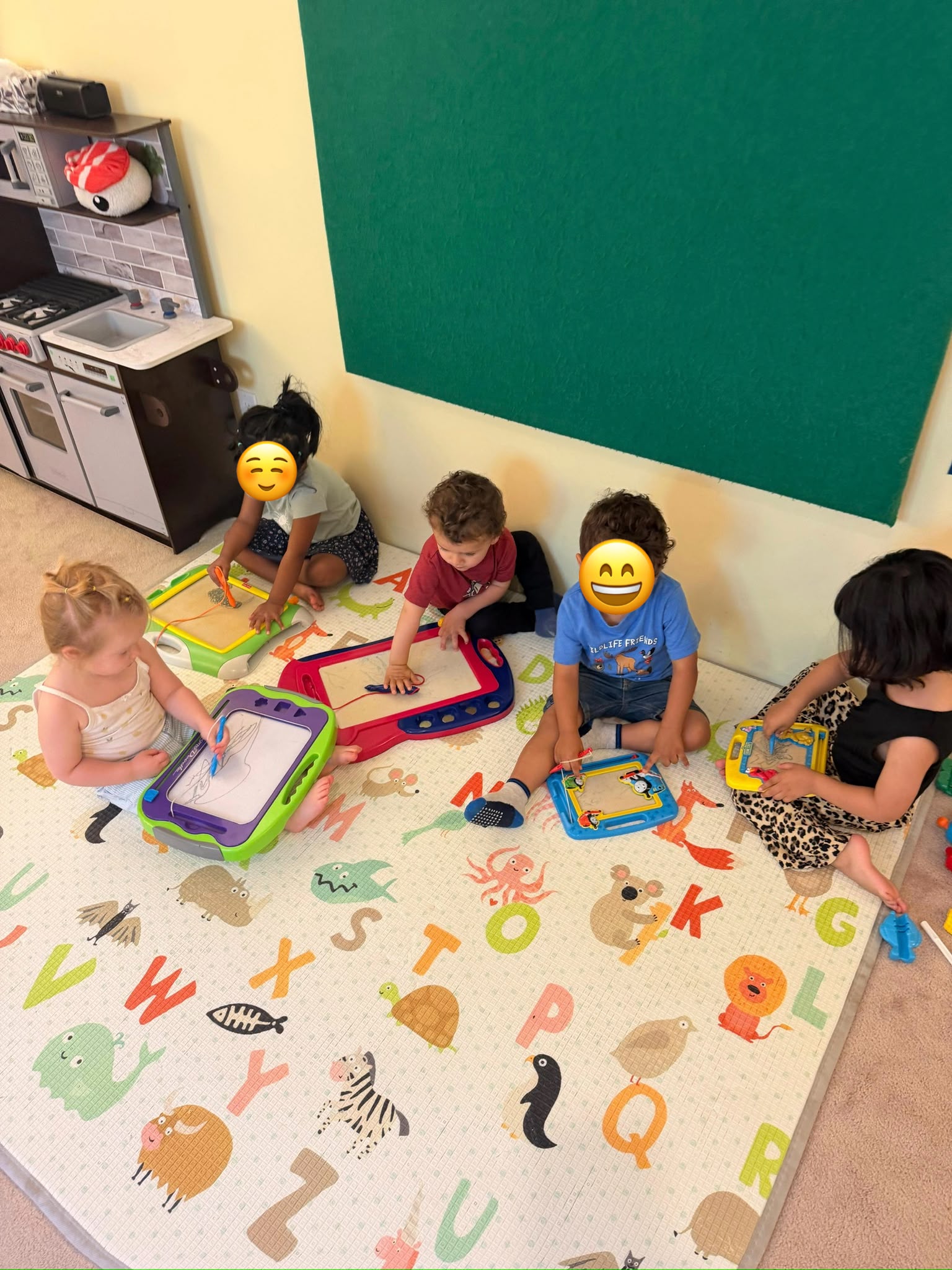 Children sitting together while drawing on magnetic boards