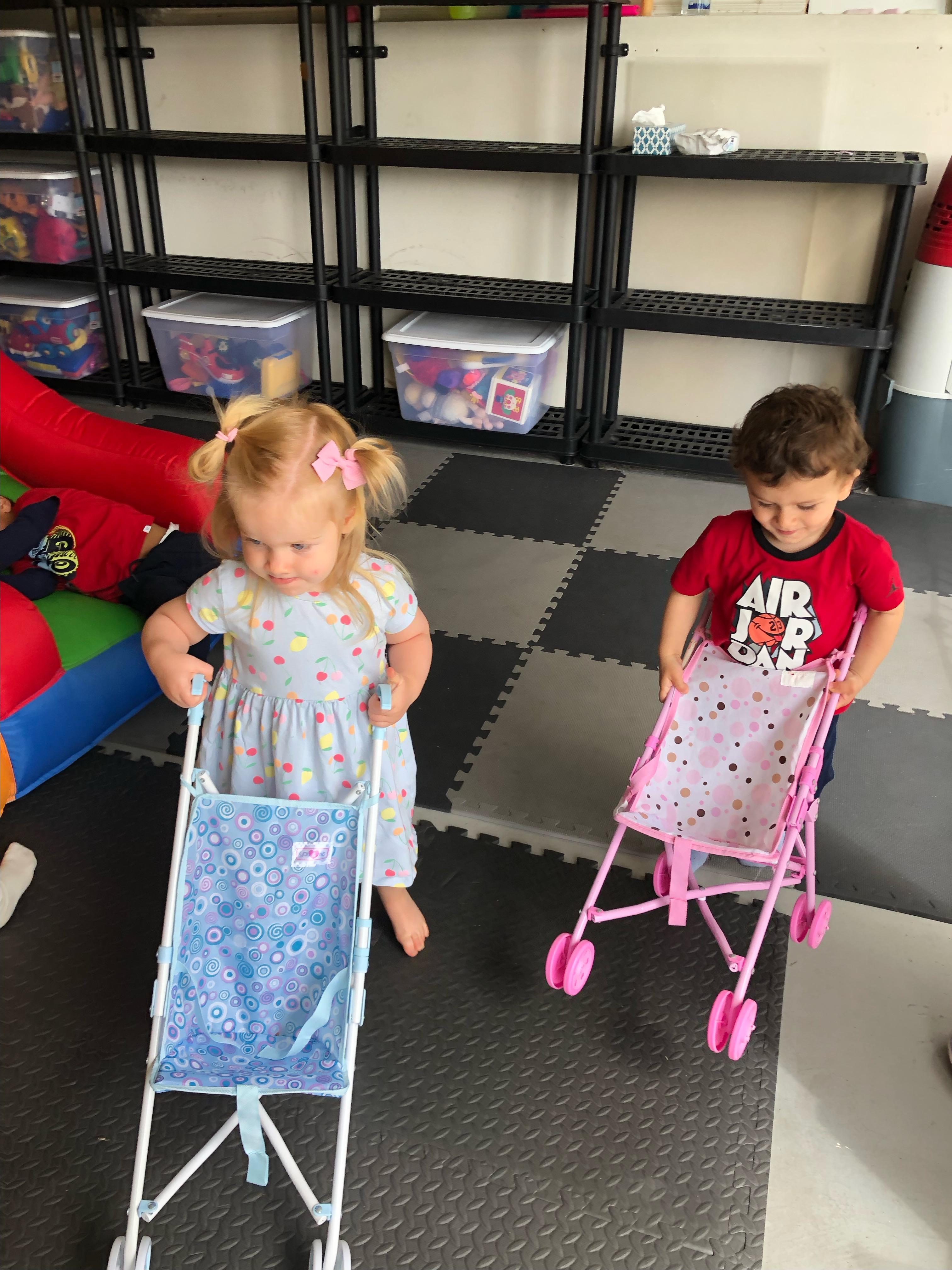Children pushing toy strollers in the playroom
