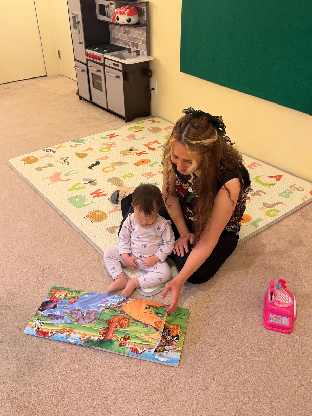 Bahar reading a story with a child on the classroom rug