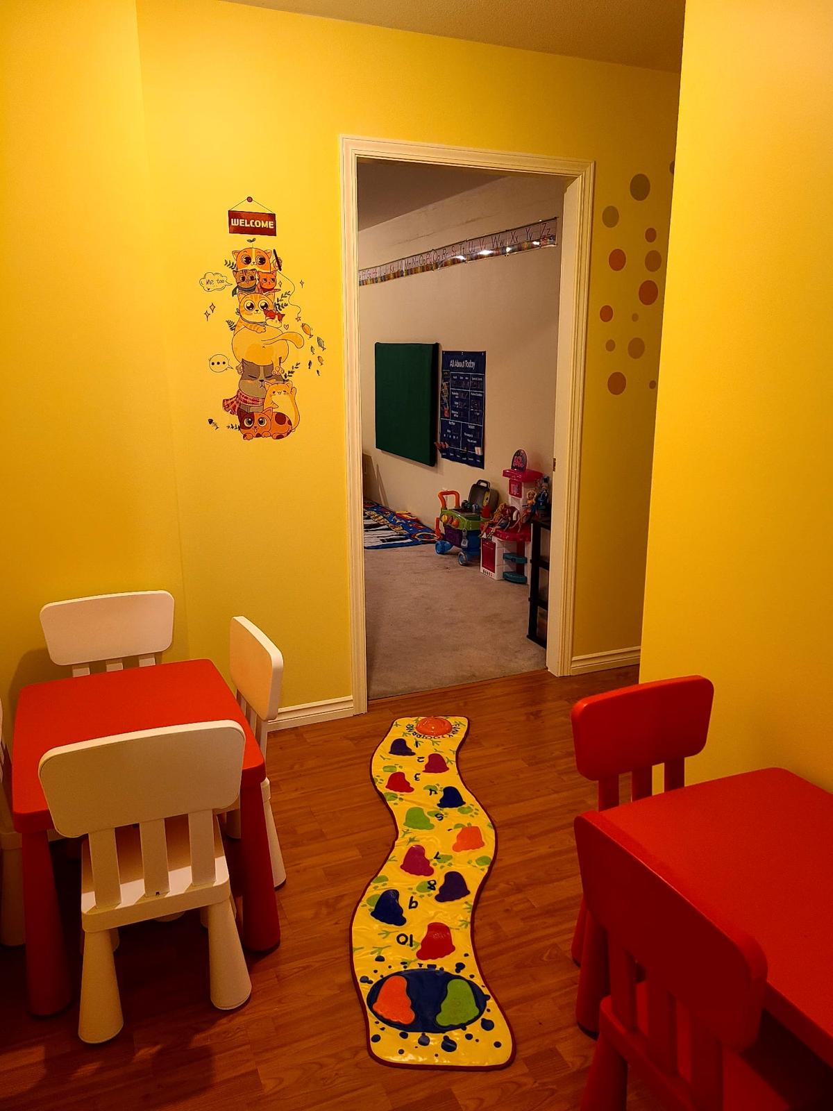 Welcoming daycare entry with child-sized tables and a path toward the play room